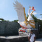 Seniman patung I Ketut Putrayasa berpose di depan Patung Angsa Putih karyanya di gerbang depan Bendungan Tamblang, Sawan, Buleleng. 
